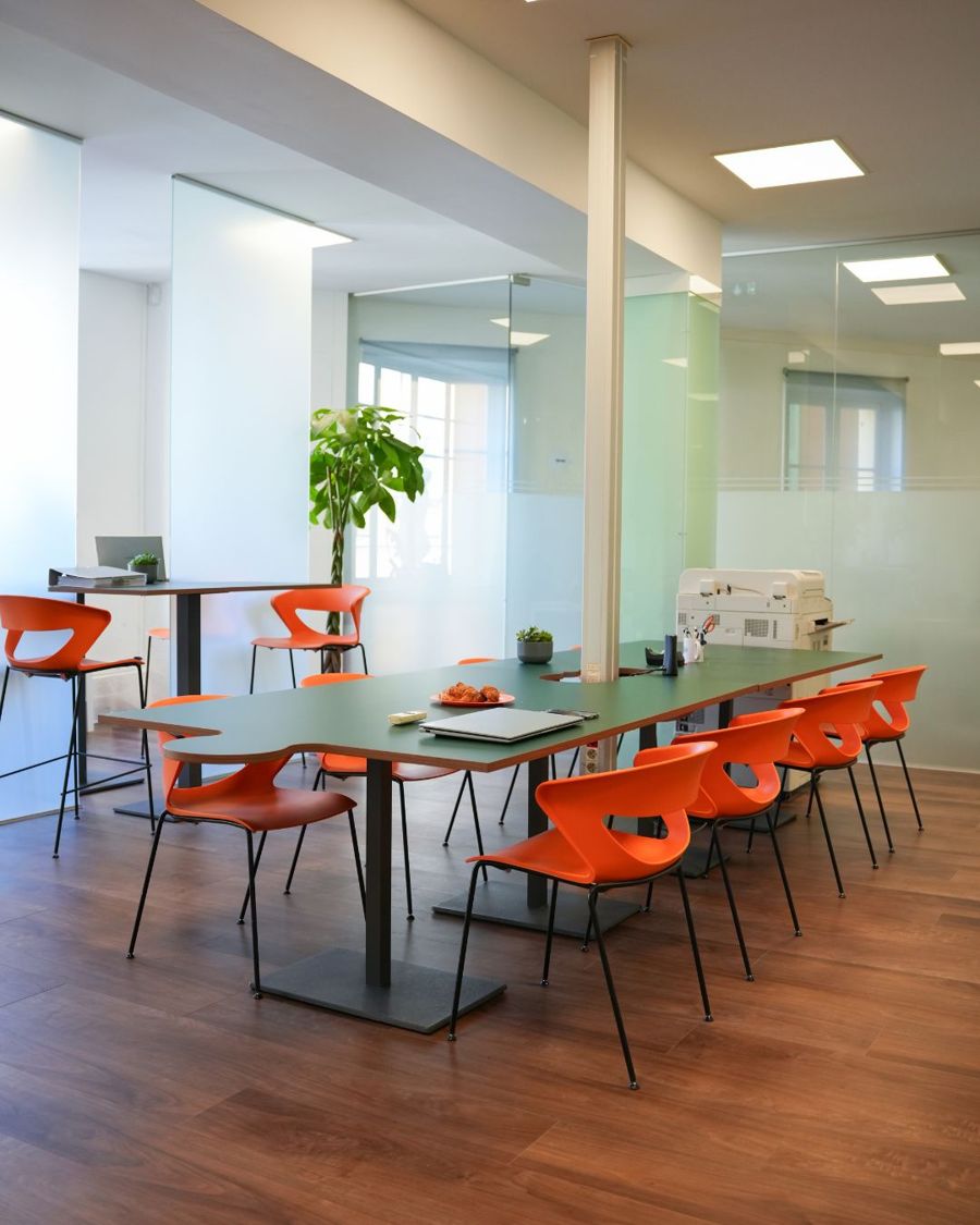 Open space de Puzzle II, tables vertes et chaises orange
