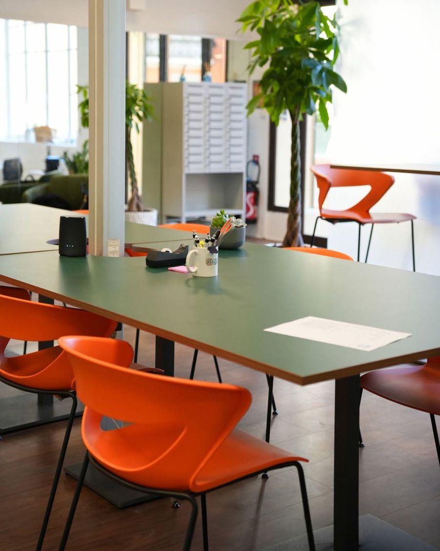 Grande table de l’open space, plantes et chaises orange